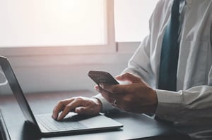 closeup-of-a-businessman-using-smartphone-and-lapt-2025-02-11-21-22-48-utc